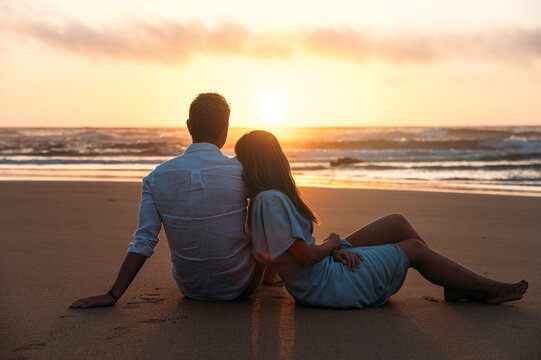 Faceless couple near sea at sundown time