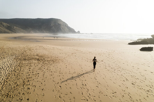 Unrecognizable woman running on sandy beach