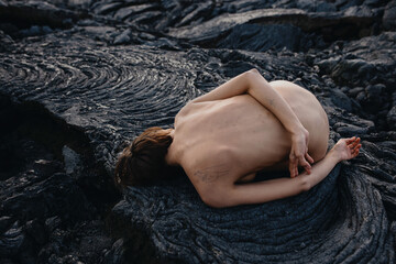 Nude female lying on black solid lava field in Iceland 