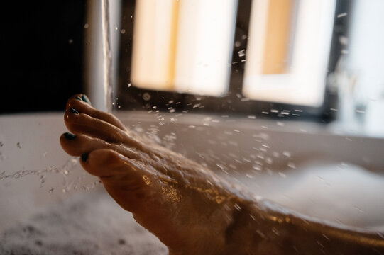 Crop woman splashing water in bathtub
