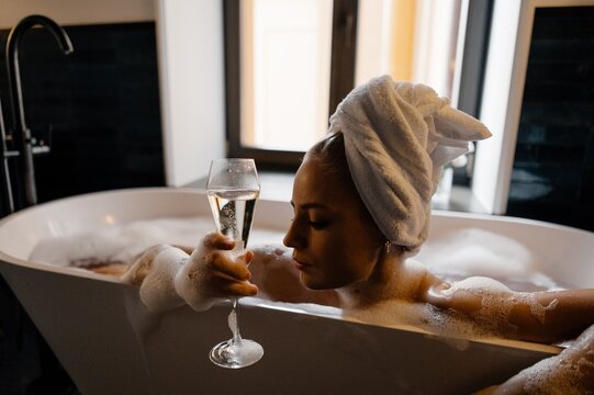 Woman with champagne relaxing in bathtub
