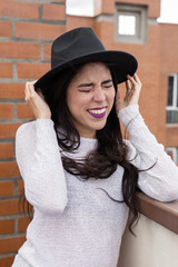 having fun holding her hat in the wind a latin woman with long wavy hair, fashion accessory, beauty