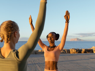Black sportswoman showing exercise to girlfriend