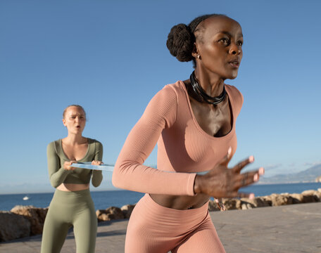 Determined sportswoman running with resistance band