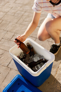 Crop woman taking beer from ice box