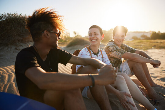 Happy friends talking during picnic on beach