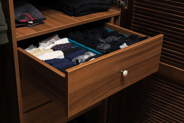 Fototapeta na wymiar Open drawer with clothes in closet