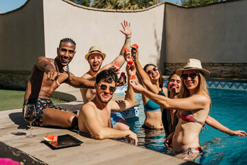 group of friends at a swimming pool smiling and waving to the camera