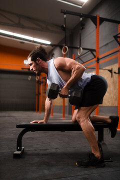 Strong man during dumbbell workout on gym bench
