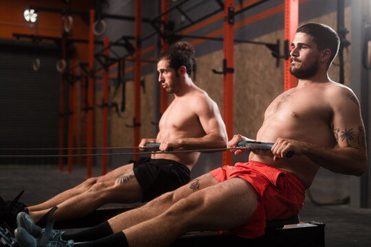 Two fit men working out on rowing machine