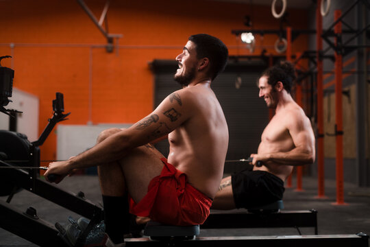 Smiling athletes competing on rowing machine