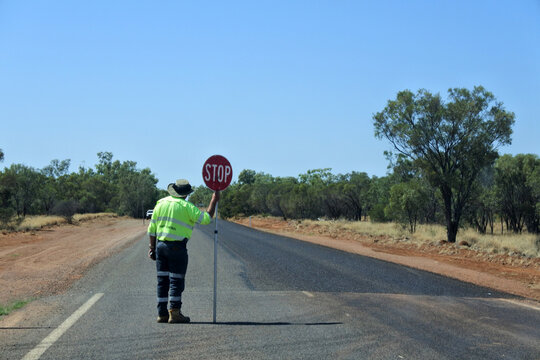 Australian Road Worker Holding A Stop Sign On An Outback Road