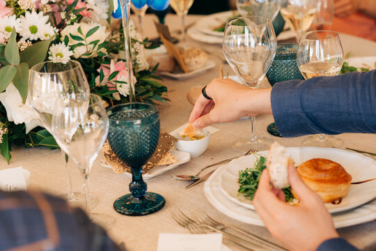Male hands dip bread in olive oil during festive dinner