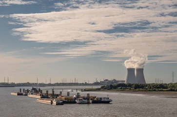 Foto op Canvas Antwerpen, Flanders, Belgium - July 10, 2022: Cooling towers and Doel Nuclear Power plant on horizon of landscape with Lilo Pier and docked barges on Scheldt river. Evening cloudscape © Klodien