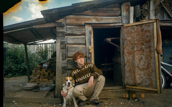 attractive rustic red-haired guy with his dog on the farm