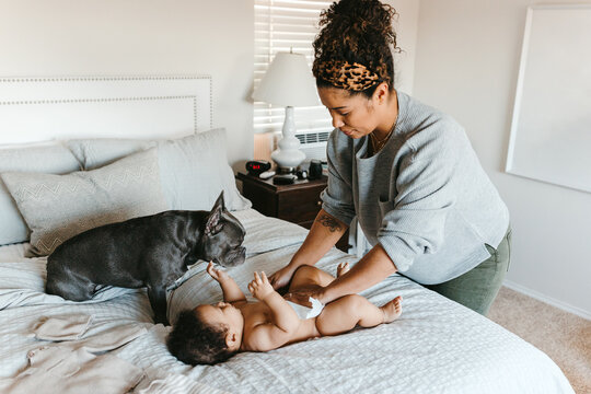 A mother with her baby son laying in the bed, changing his diaper