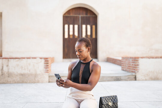elegant black woman with mobile phone in the city