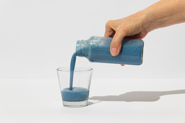 Woman pouring blue spirulina healthy superfood drink into glass
