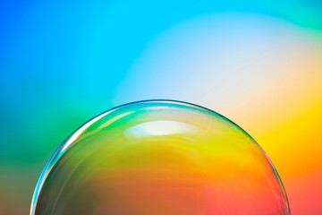 Transparent soap bubble on rainbow background.