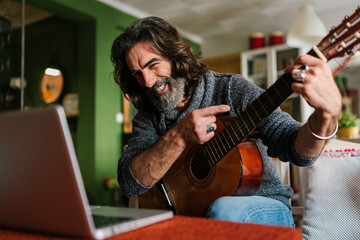 Positive man playing guitar during video call