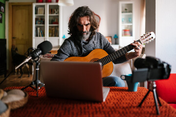 Mature male guitarist using laptop