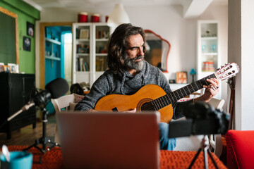 Middle aged vlogger practicing to play guitar