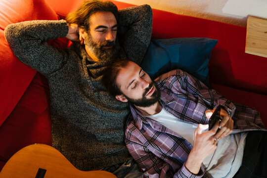 Men browsing smartphone near guitar