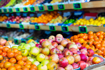 Bunches of various fresh fruits on shelves in salesroom of greengrocer.