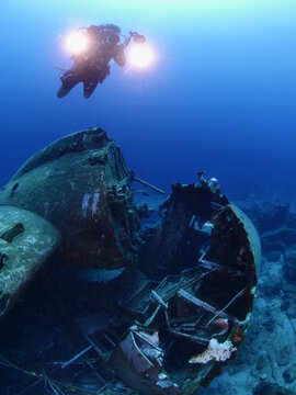 scuba divers exploring airplane wreck underwater taking photos of c47