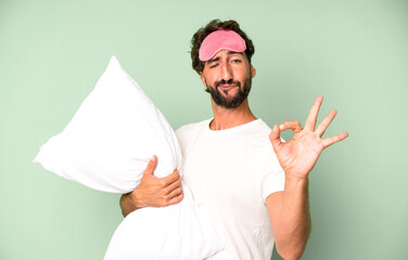 young crazy bearded and expressive man wearing pajamas and eye mask and with a pillow