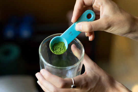 Hands Holding A Measuring Spoon Of Matcha Powder