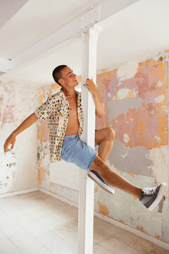 Happy guy practicing pole dance in studio