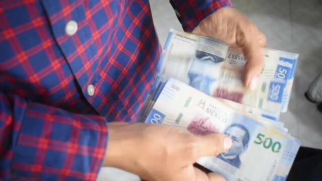 Manos de un joven hombre caucasico contando billetes de quinientos pesos mexicanos 