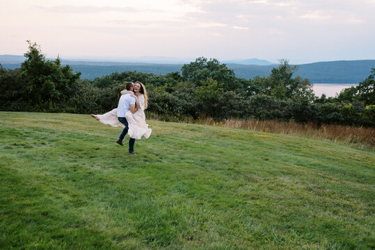 Man carrying fianc&eacute; in dress while both are laughing together