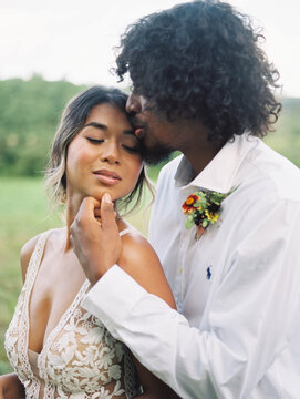Portrait of a groom kissing his bride sensually on her temple