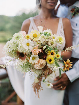 close up of a bride and groom hugging with wedding bouquet in focus
