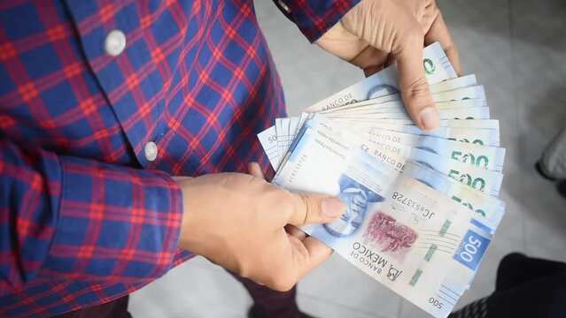 Plano detalle de las manos de un hombre mostrando varios billetes de 500 pesos mexicanos 