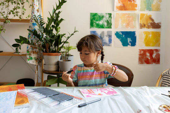 Little girl painting with watercolor brushes