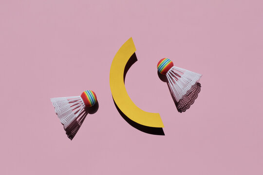 Two badminton shuttlecocks with geometric details on pink background