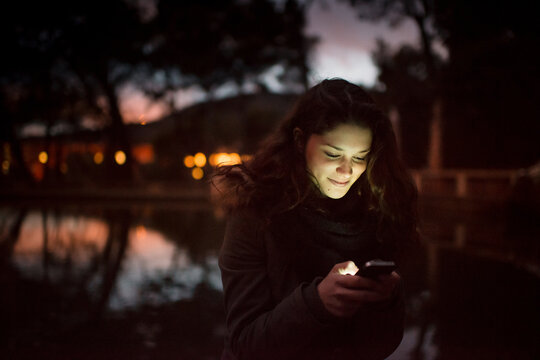 Smiling woman with cellphone illuminating her face