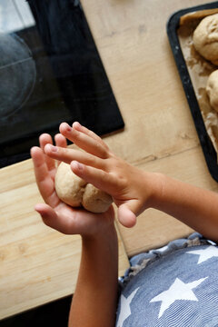Crop child rolling bun from dough