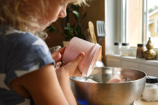 Girl adding flour into bowl