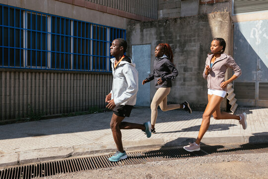 Black Athletes Jogging In Industrial District