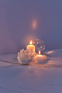 Candles burning in dark near crystals and glass ball