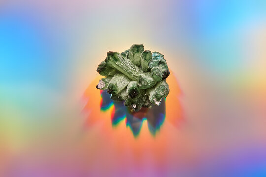 Natural green mineral on shiny holographic background