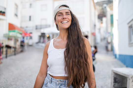 portrait of young woman with long hair and cap in the city