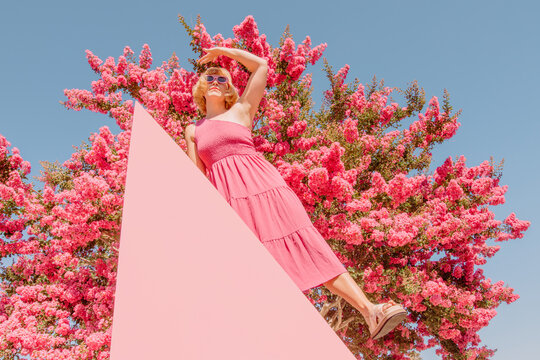 Girl poses with triangle in front of pink tree