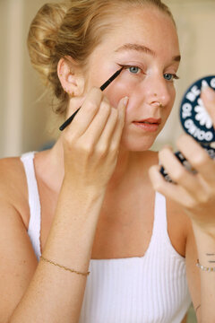 young woman applying eyeliner