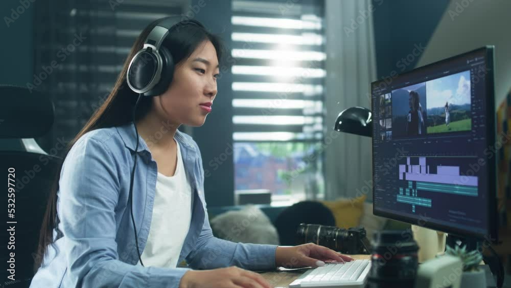 Wall mural female asian freelancer editing video for customer or travel blogger in program on computer while si