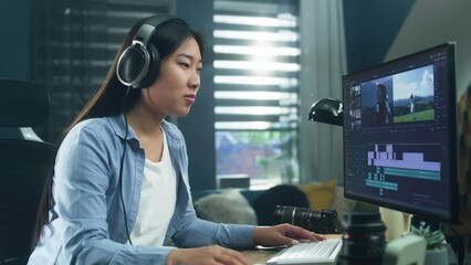 Female asian freelancer editing video for customer or travel blogger in program on computer while sitting at the table and working at home